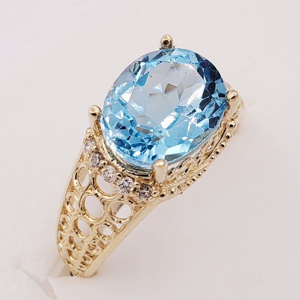 14kt yellow gold ring with one prong set oval cut natural blue topaz and diamonds (0.15cts)